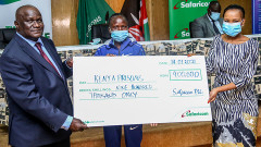 Safaricom PLC Sponsorship Manager Peris Nduta Muhoro (right) presents a dummy cheque worth Sh900,000 to World Cross Country Bronze Medallist Lilian Kasait (centre) and Commissioner General Prison Service Wycliffe Ogallo at Magereza House. PHOTO/SAFARICOM