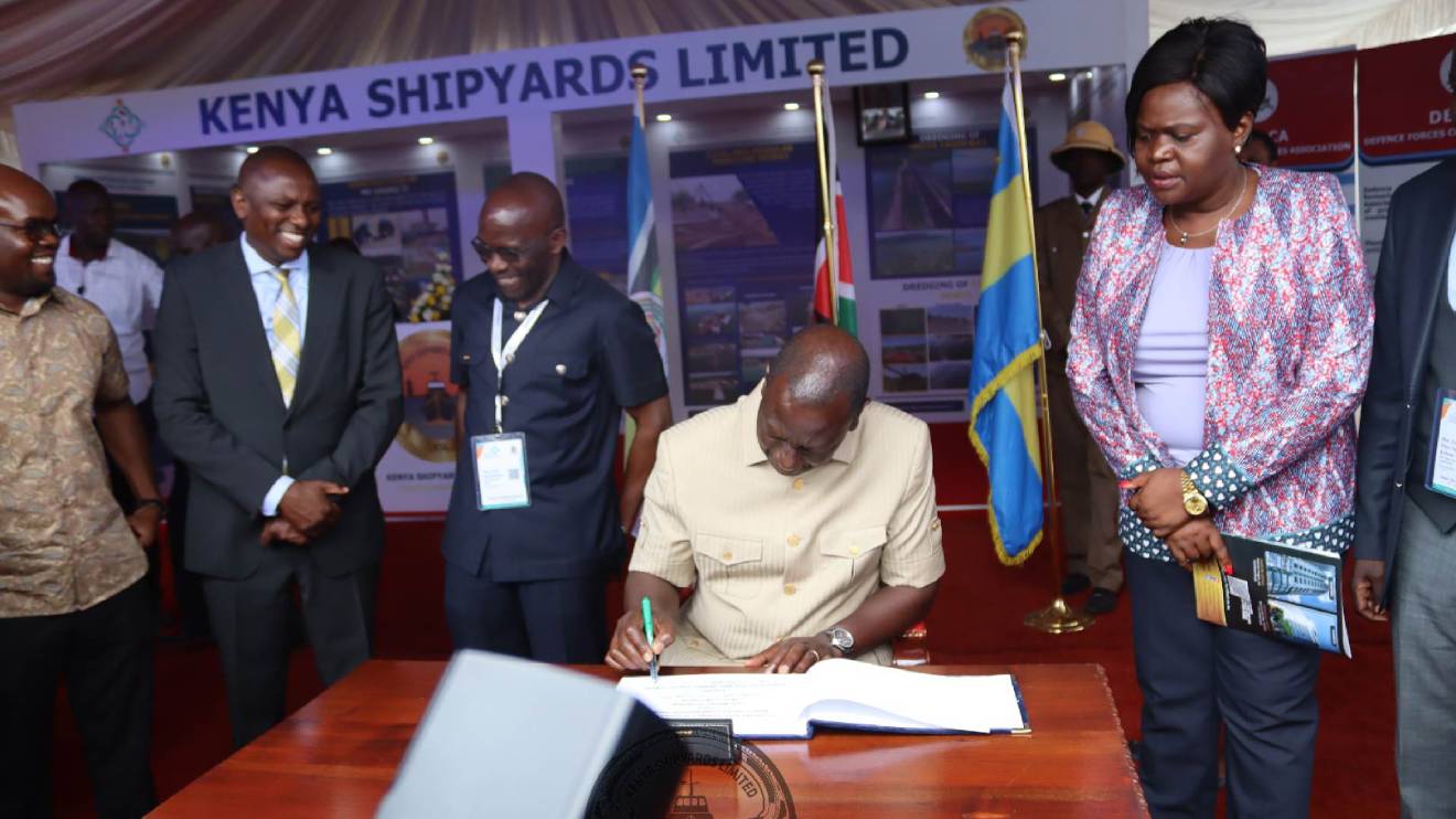 President William Ruto signing the visitor's book at the Kenya Shipyards Limited and looking on is Gladys Wanga, Raymond Omollo, Kimani Ichung'wah and Paul Otieno. PHOTO/COURTESY