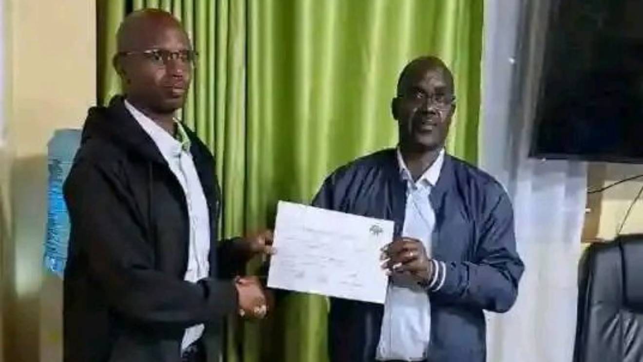 John Chebochok (Right) receiving his certificate from an IEBC officiall PHOTO/COURTESY