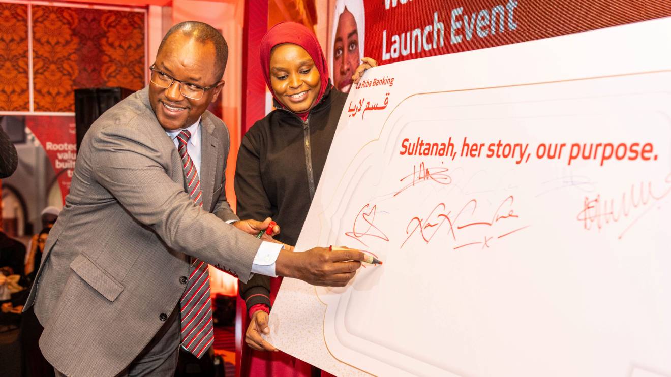 Yusuf Omari, signs the commitment board during the launch of the La Riba Sultanah, Kenya’s first Shariah-compliant bank account designed to cater to women entrepreneurs. Looking on is Absa Bank La Riba Banker Lutfa Anas Ali. PHOTO/COURTESY